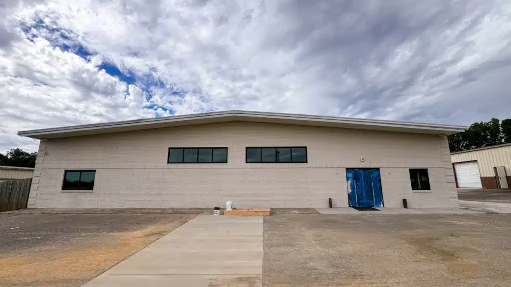 Front view of a commercial building with a newly painted light brick facade and paint supplies.