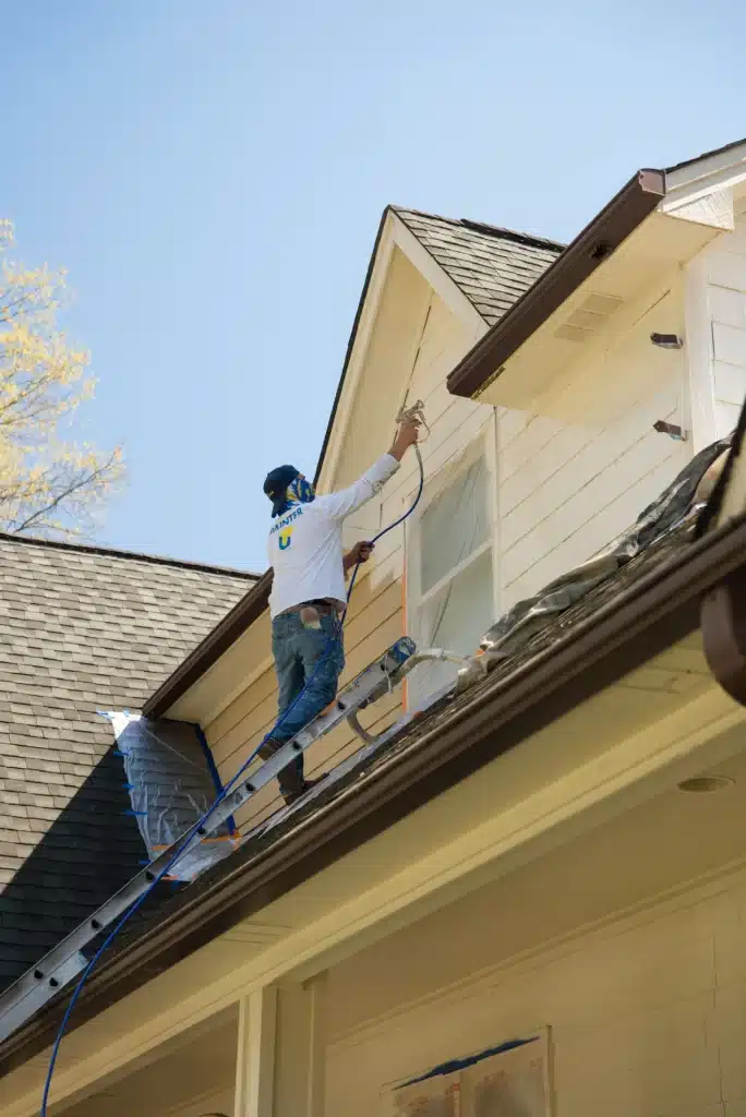 Painter working on exterior siding of a home