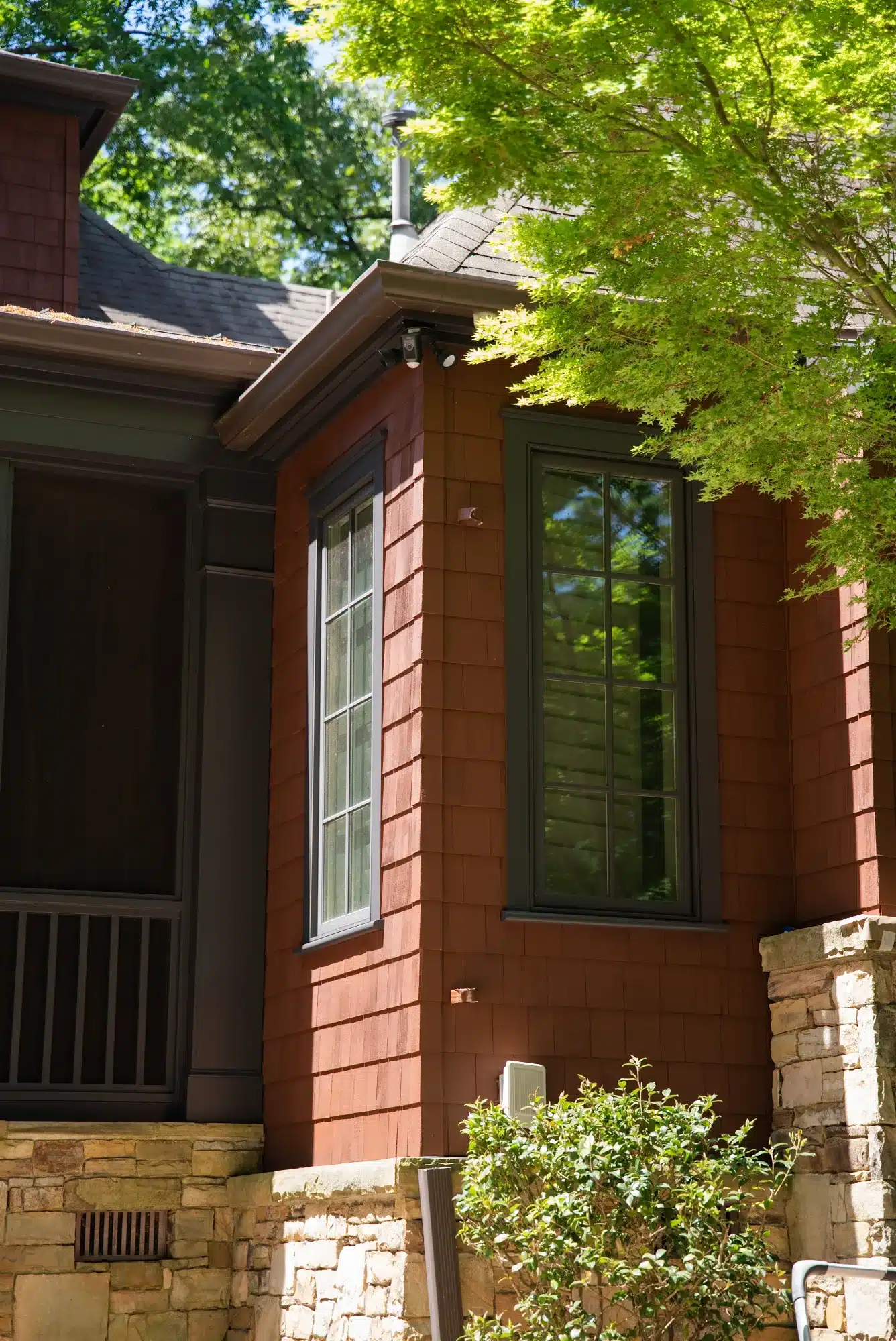Rust Red Exterior Residential Siding Rust red-painted residential exterior with dark green window frames and stone foundation trim.